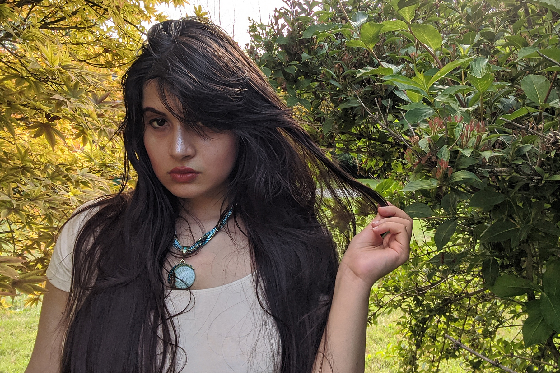 Komal Ashfuq poses for a photo in front of trees.