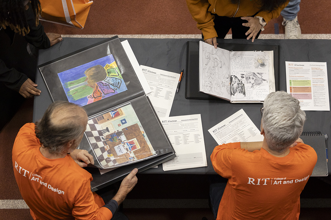 An overhead view of RIT faculty reviewing portfolios.