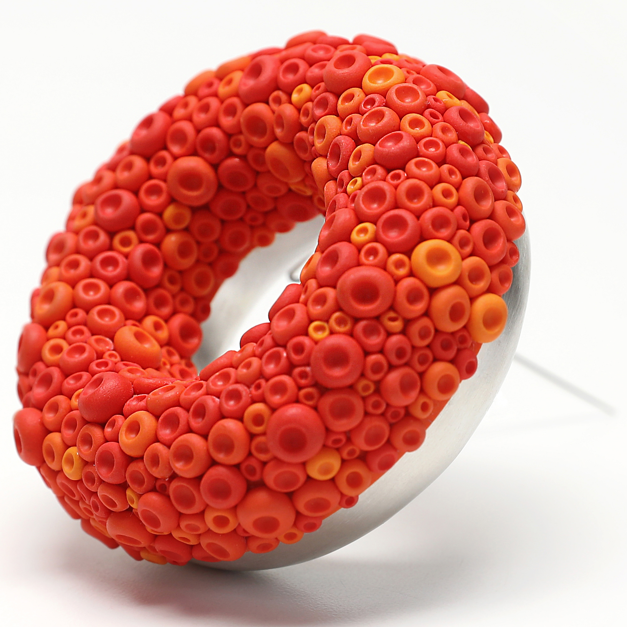 A round earring with vibrant red and orange design elements.