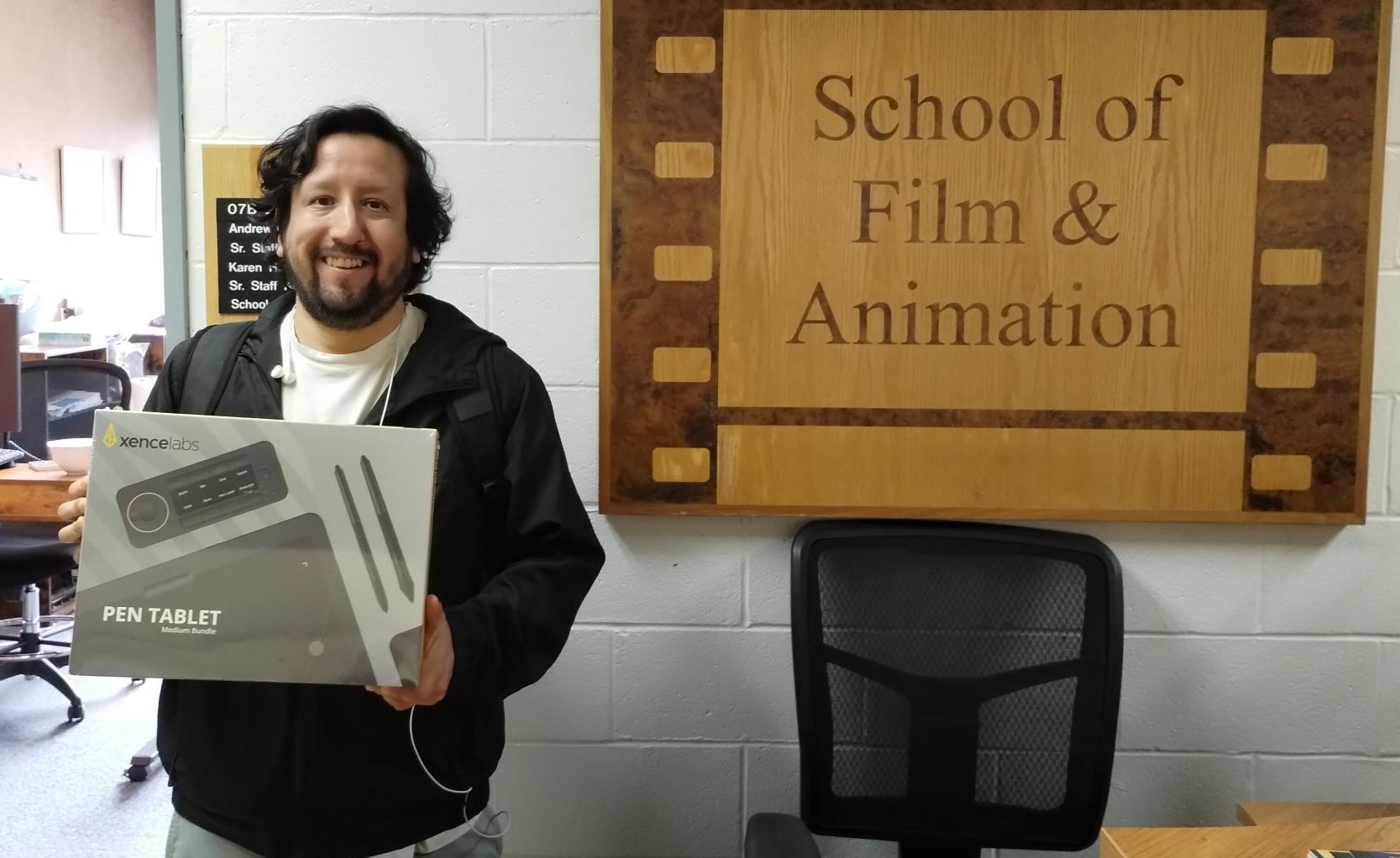 A student holds up a box with a pen tablet inside.