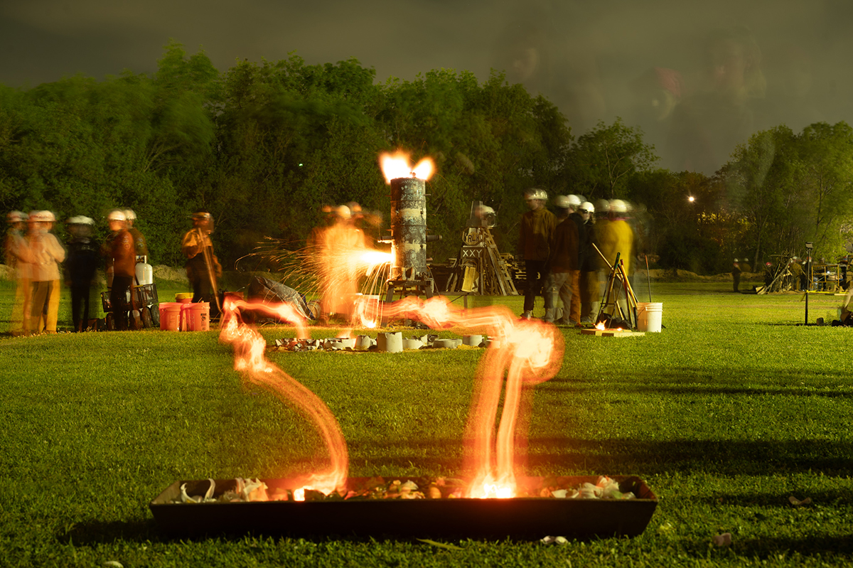 A furnace melts iron and is poured into a bed of flowers.