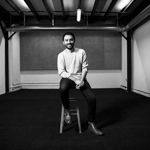 Sinan Dagliu sits on a stool for a portrait.