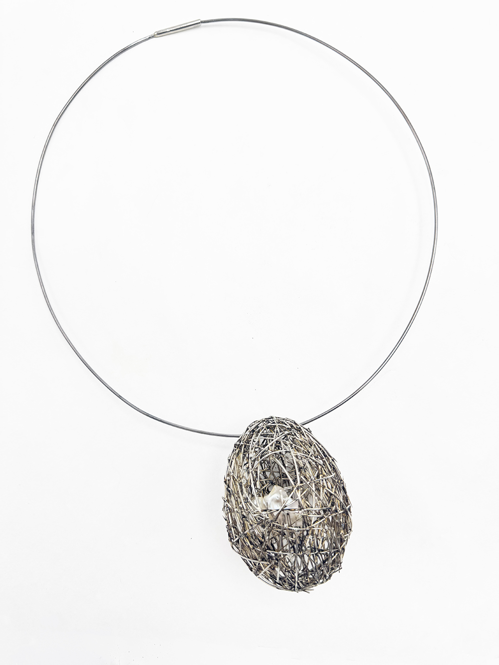 A silver necklace with a pendant that resembles a bird's nest.