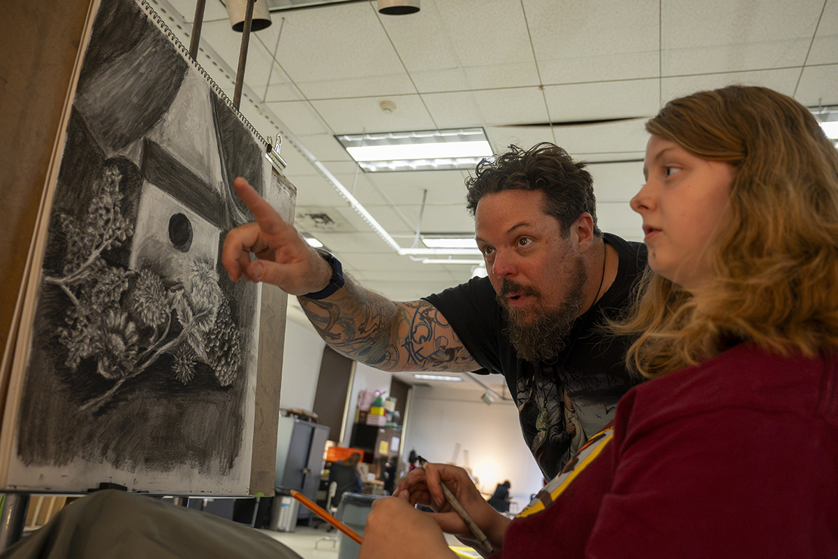 An instructor works a student through their drawing.