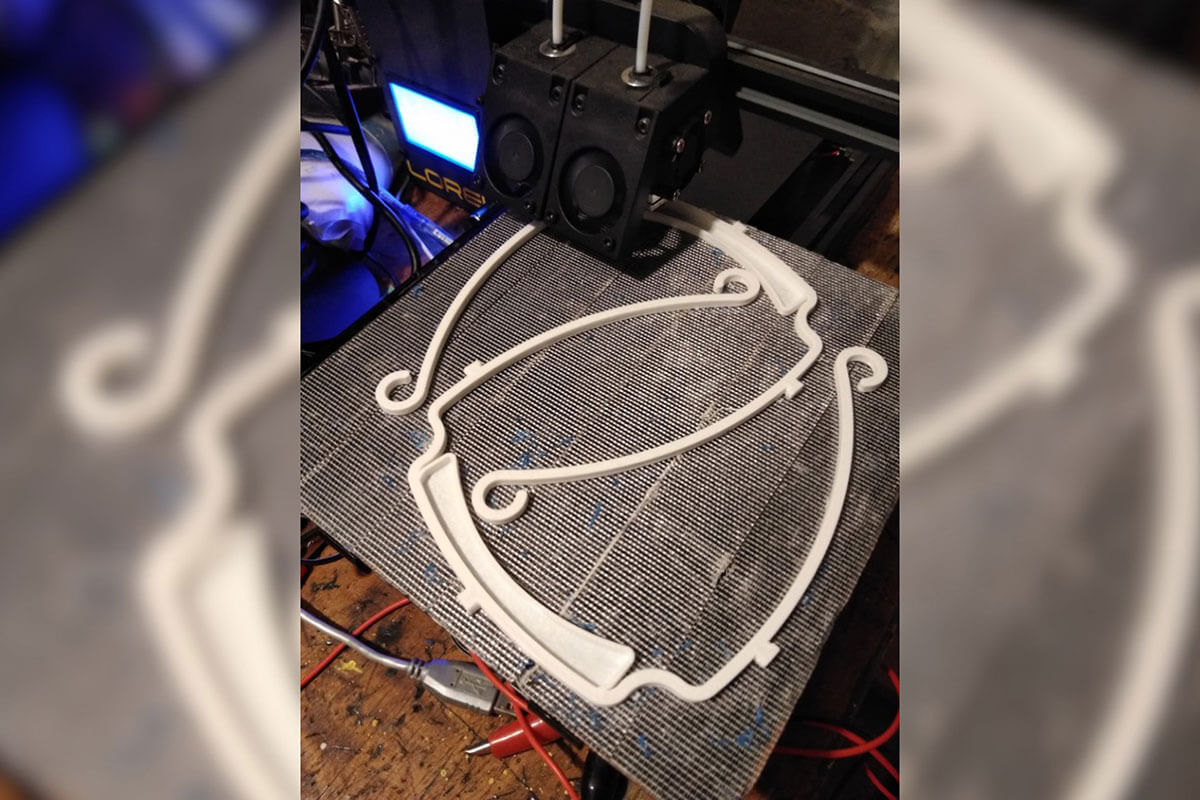 A 3D printer finishing a print of two face shield headbands.