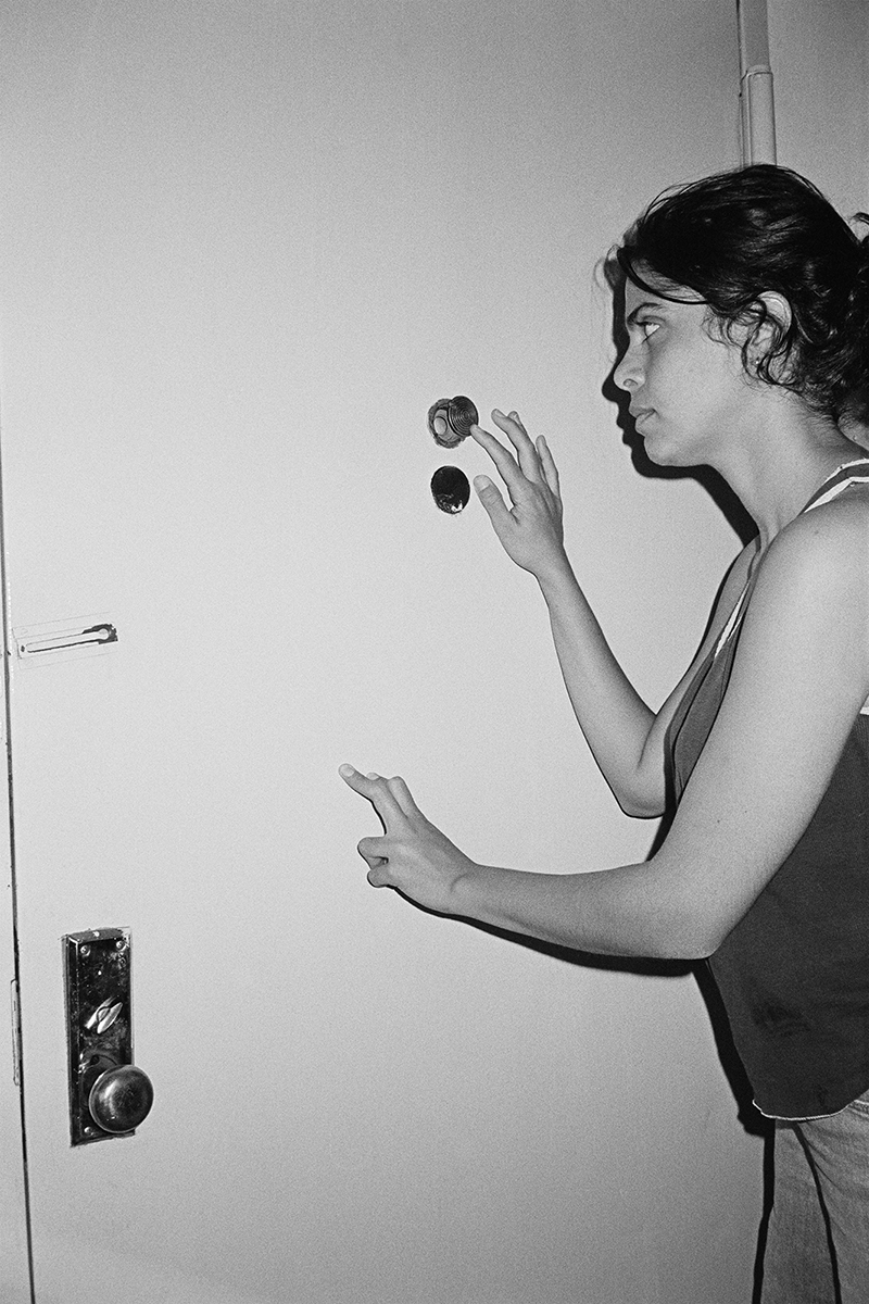 A person looks through the eye hole on a door.