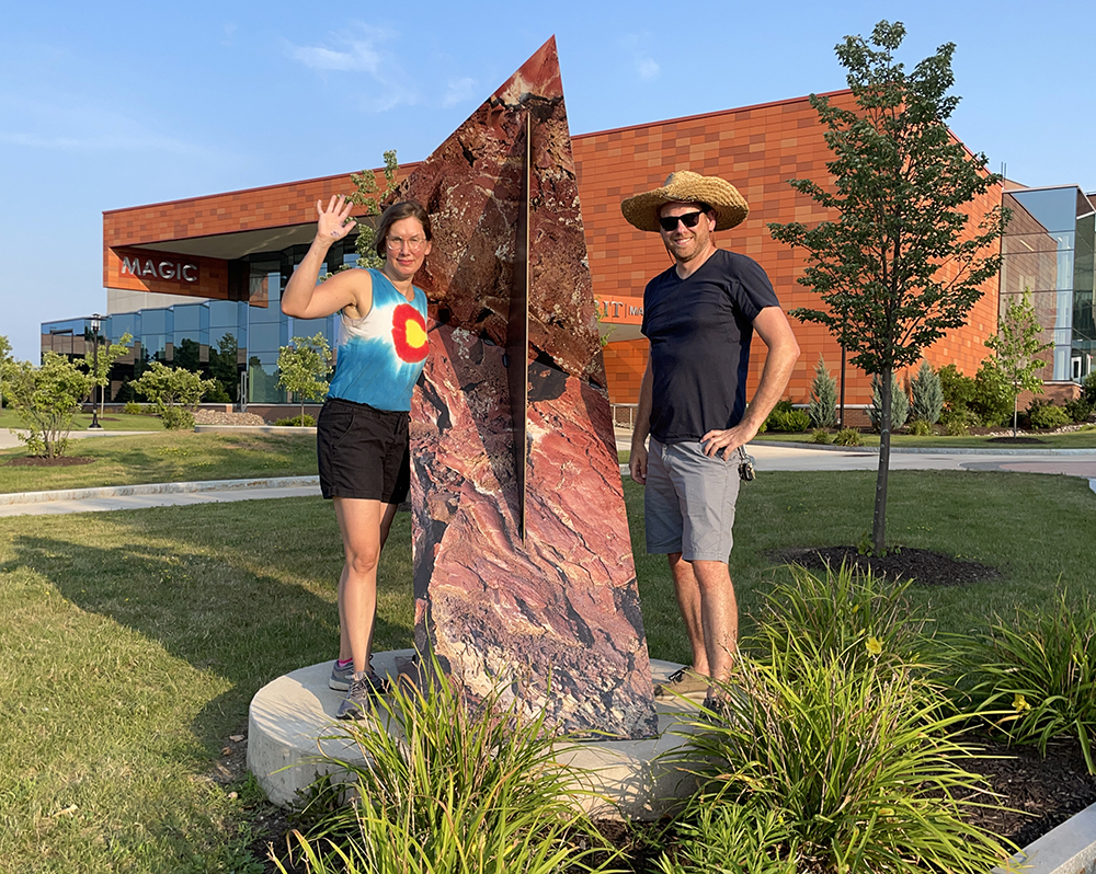 Letha Wilson and John Aasp stand next to Wilson's sculpture on the RIT Campus