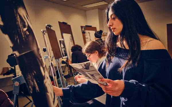 A students draws at an easel.