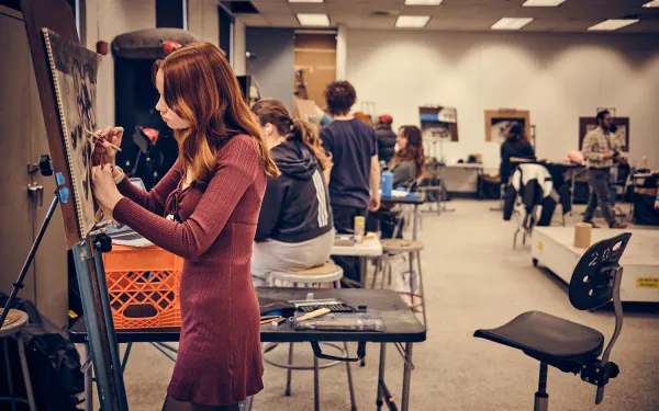 A drawing class works at easels.