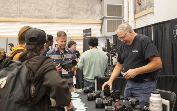 A camera rep shows off cameras to trade show attendees.