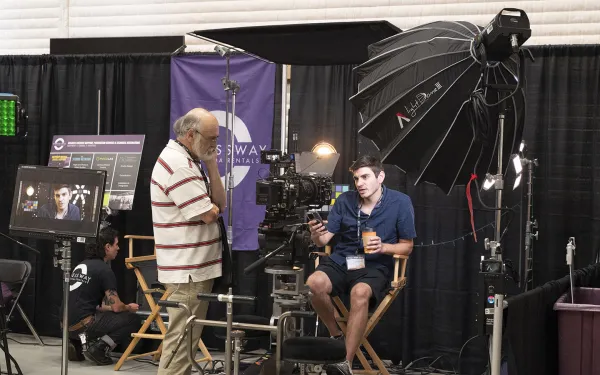 A person sits on a director's chair as light shines down.