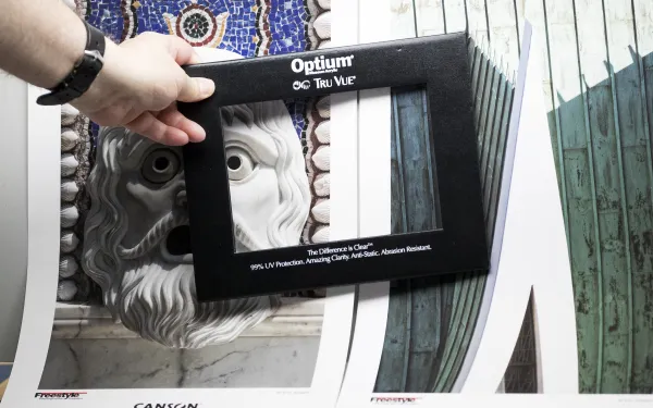 Someone places a picture frame over objects at a photo trade show.