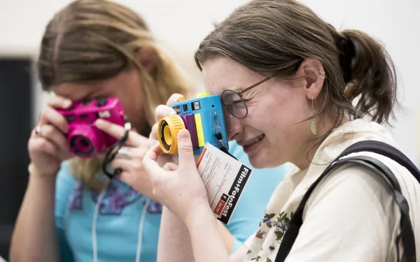 Two people operate cameras.