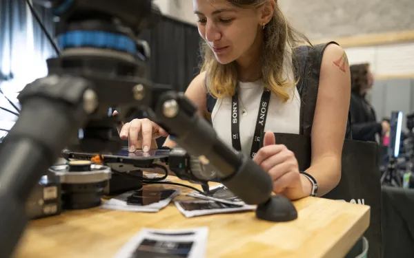A smiling student looks at camera equipment.