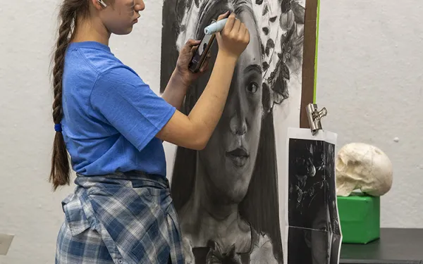A student draws a self-portrait.
