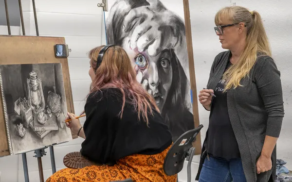 Instructor Angie Carter talks with a student about their drawings.