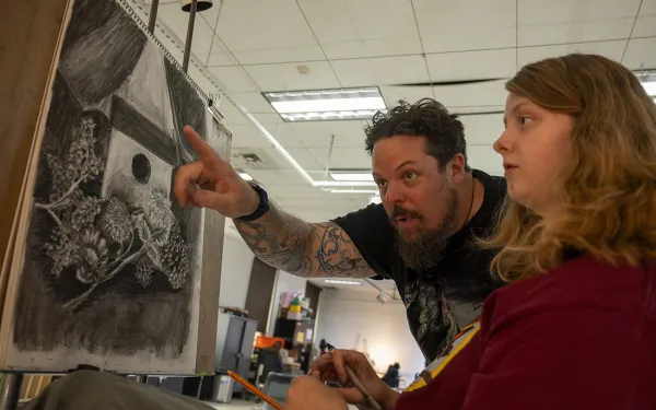 MFA student Jason Ferguson instructs a student on drawing.