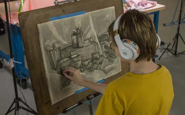 An overhead view of a student drawing a still life.