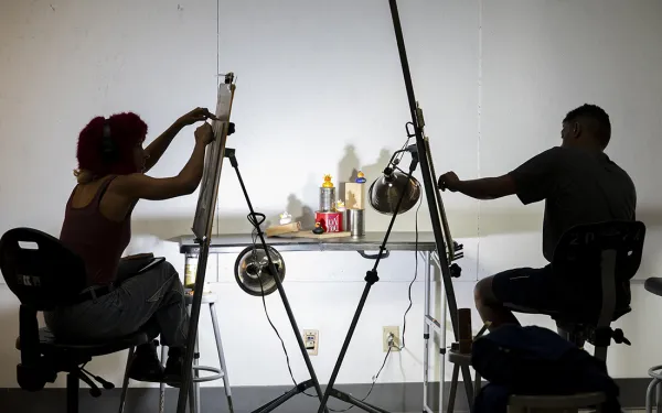 Two silhouette of artists work at easels.