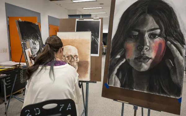A student draws skulls and a self-portrait.