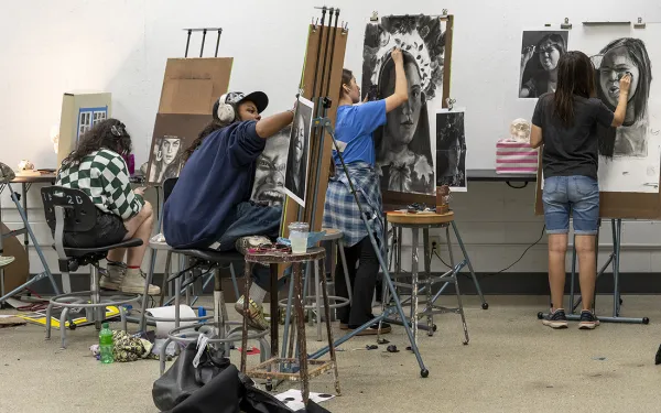 A group of students work at easels.