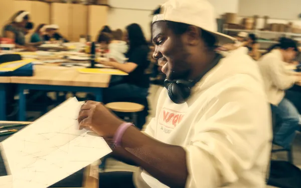 An RIT student smiles while working on a 2D Design project.