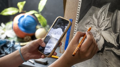 A student draws from a reference on their phone during RIT's Pre-college Portfolio Prep Workshop.