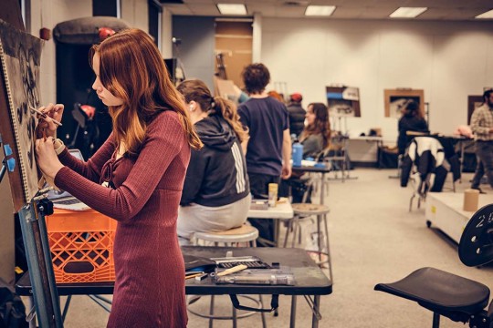 A group of students drawing at easels in a studio space.