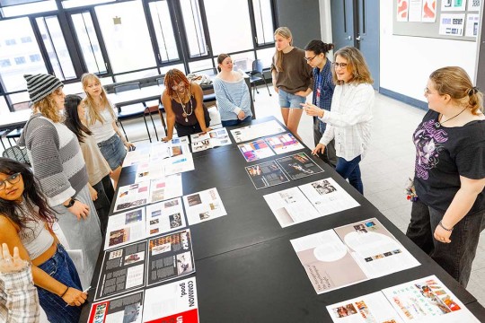 students gather around a large table with samples of magazine spreads.