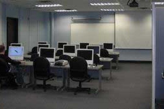 Mac lab with a student sitting at a computer in the back of the room