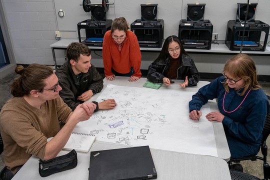 A group of students in a studio sketching on large paper.