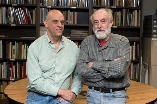 Daniel Burge, left, and Jean-Louis Bigourdan in button down shirts standing in front on books.