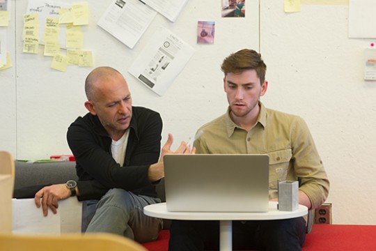 Faculty Josh Owen observes what's on a computer screen with a student.