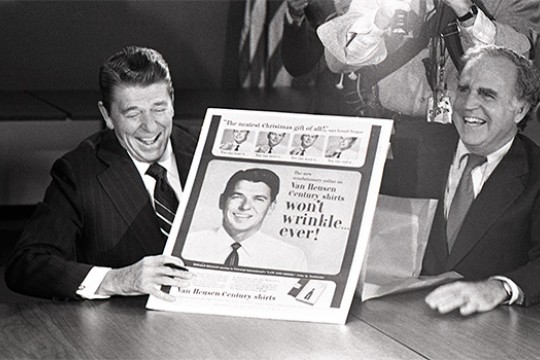 President Ronald Reagan holding poster at table