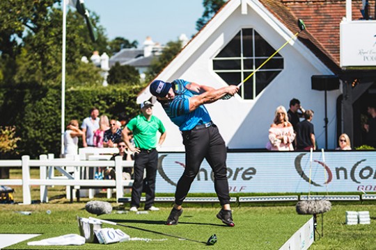 Ryan Steenberg hitting a golf ball at a competition, his arm and club still extended in the air.