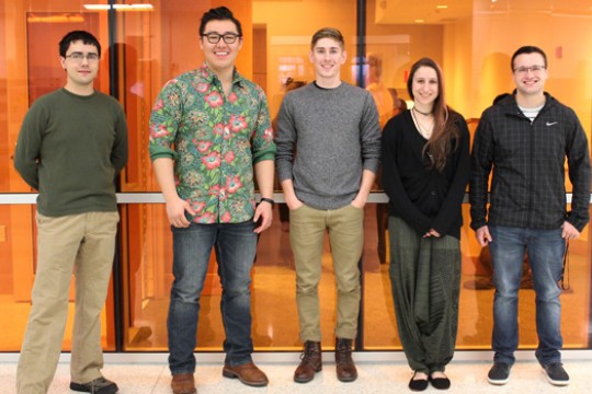 The winning orange juice team poses for a photo together with an orange backdrop.