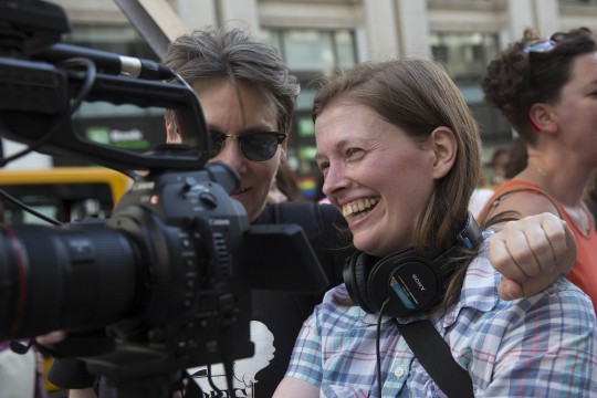 Rossman stands behind a camera laughing