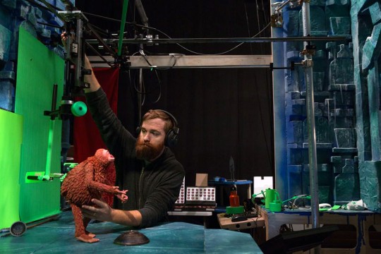 Man works on staging model of claymation monkey.