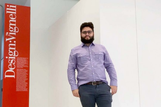 A male student stands next to sign.