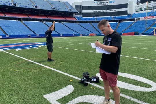 two men stand on the 50 yard line of highmark stadium