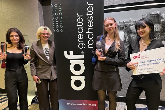 A group of students pose with hardware and a large check.