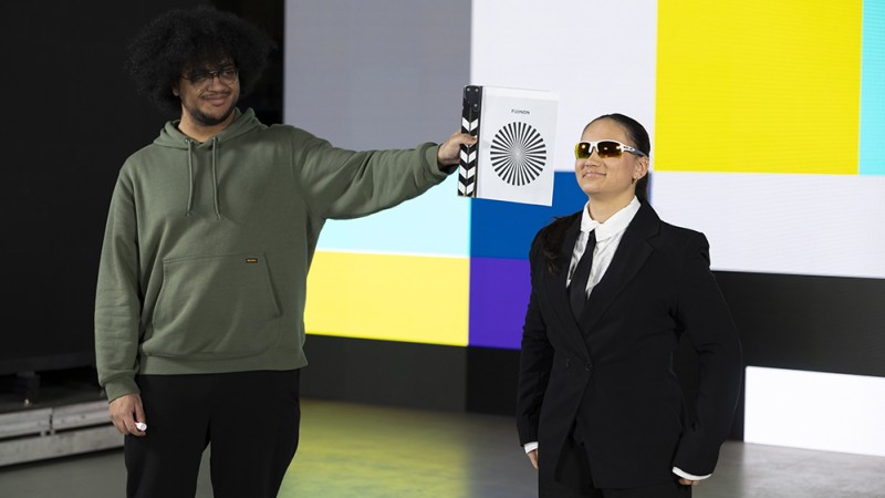 Two students stand in front of a giant LED virtual production screen.