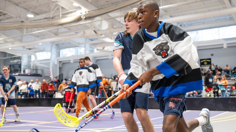 Floor hockey players run next to each other.