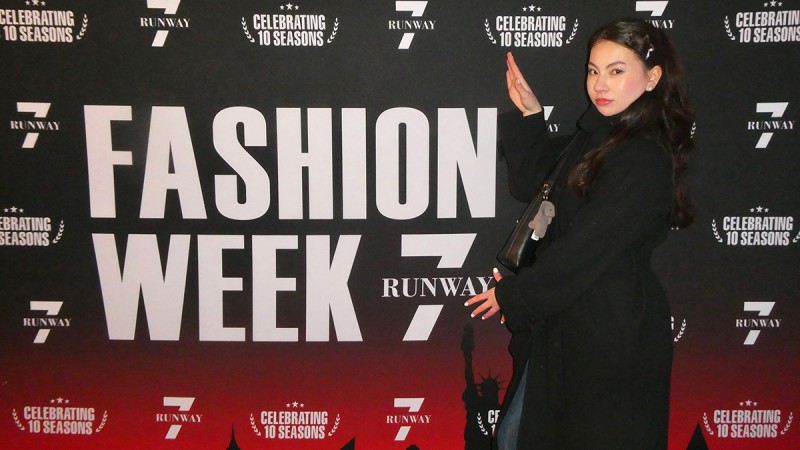 Shannon Lesch stands in front of a Fashion Week banner.