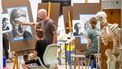 Denton Crawford, faculty, teaches students drawing techniques in a studio.