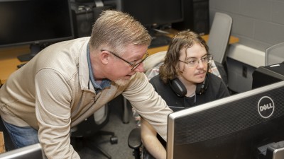 Craig Foster instructs a student while they work on the computer.