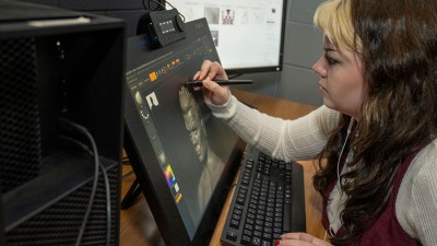 A student touches up a project on a tablet.