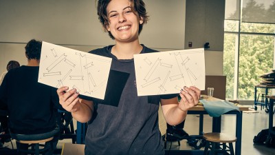 An RIT students holds up their designs they drew.