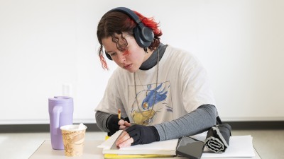 A student uses a ruler while drawing on paper.