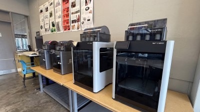 A row of 3 D printers in a studio space.